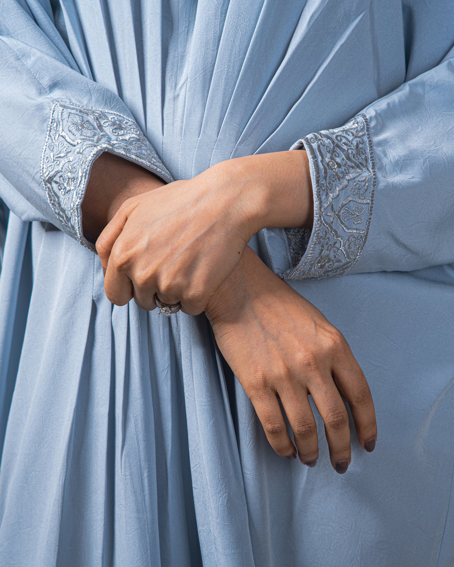 Close-up of a person wearing a light blue garment with embroidered cuffs.