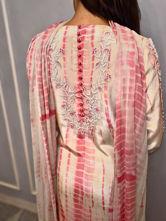 This elegant three-piece ensemble showcases a unique tie-dye pattern in soft cream and delicate rose hues with hand & neck handwork (zardousi work), creating a graceful and contemporary look. Intricate floral embroidery adorns the sleeves and extends to the back of the kurta, adding a touch of traditional artistry and refined detail. Delicate button accents further enhance its sophisticated charm.
Paired with comfortable bottoms and a matching dupatta, this set is perfect for celebrating special times