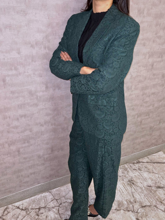 Step into sophisticated elegance with this captivating deep green pantsuit. An intricate tapestry pattern graces the luxurious fabric, whispering quality while lending unique visual depth. The impeccably tailored silhouette balances modern structure with inherent feminine grace, designed to move fluidly with poise. This stunning ensemble speaks volumes of quiet confidence and undeniable allure.
