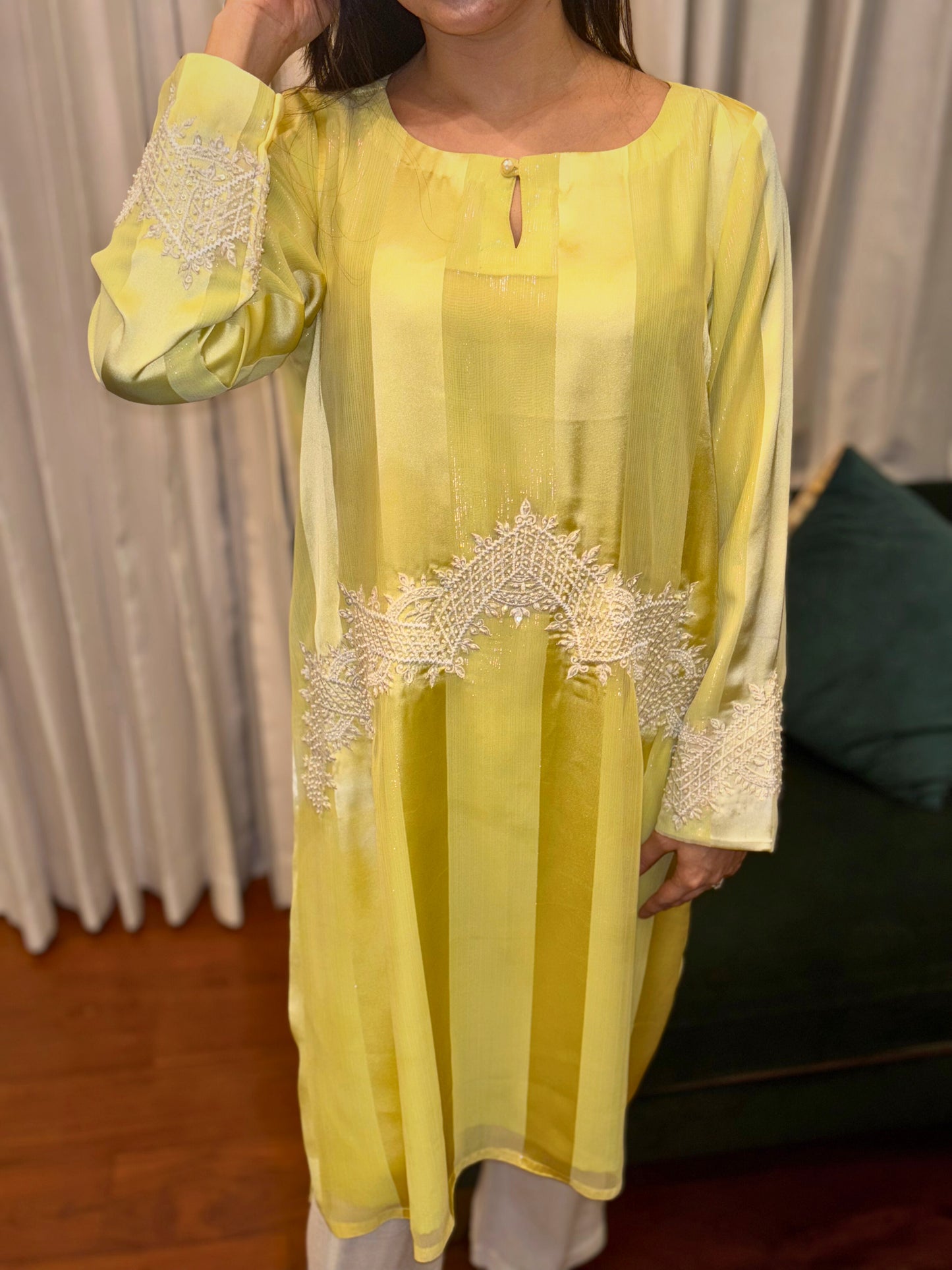 Elevate your wardrobe with the Citrus Beam Kurti Set, a lemon yellow kurti set designed for effortless sophistication. Crafted from lustrous striped fabric, this long kurti set features intricate ivory embroidery and handwork (Karchupi) across the waist and sleeves—balancing minimalism with detailed craftsmanship.
Ideal for festive gatherings or formal daytime occasions, this embroidered kurti set for women is a refreshing take on contemporary ethnic wear.