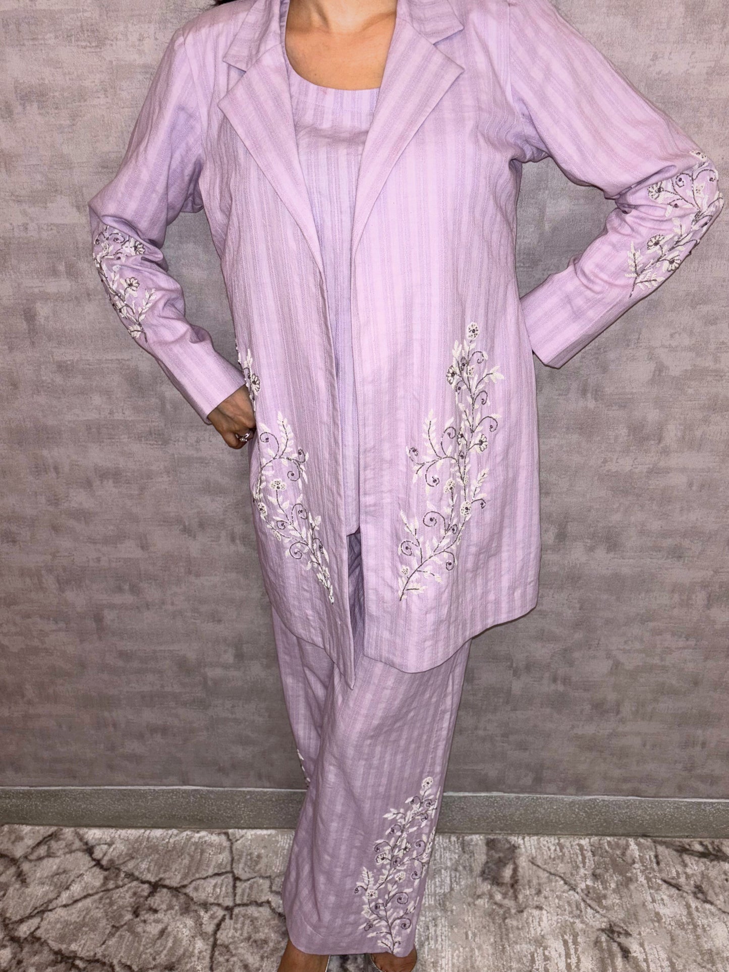 From Taraashi's exclusive Platinum Collection, this charming lilac ensemble offers sophisticated ease. Subtle stripes meet delicate silver or white embroidery gracing the flowing jacket and trousers. The three-piece set blends soft texture with intricate artistry for a light, airy feel. Experience effortless elegance and the refined quality unique to our Platinum pieces.