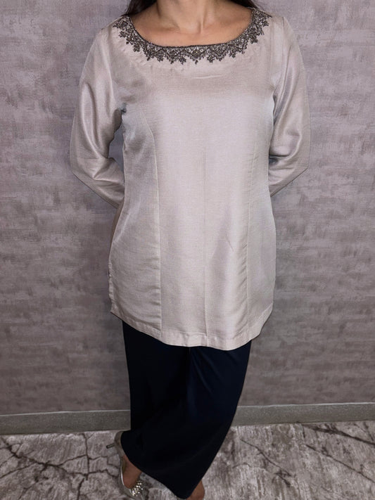 From Taraashi's exclusive Platinum Collection, introducing the Platinum Sheen Set. This elegant ensemble glows with a soft, metallic luster in a sophisticated neutral hue. The smooth fabric drapes beautifully in a chic tunic and matching trouser silhouette. Intricate dark embroidery adorns the graceful neckline, adding a touch of captivating contrast. Experience refined luxury and effortless poise unique to our Platinum designs.