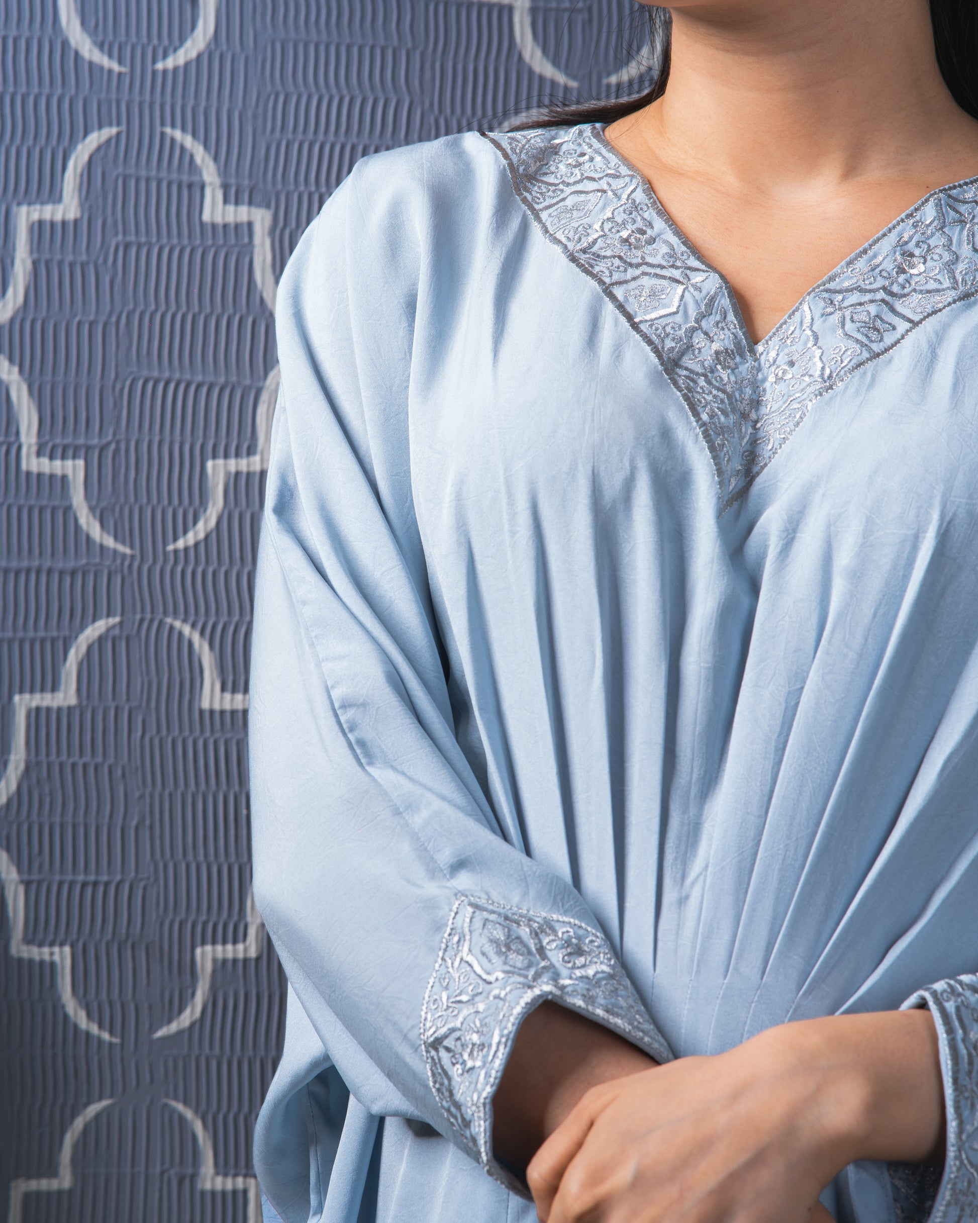 Light blue dress with lace details against a textured gray background