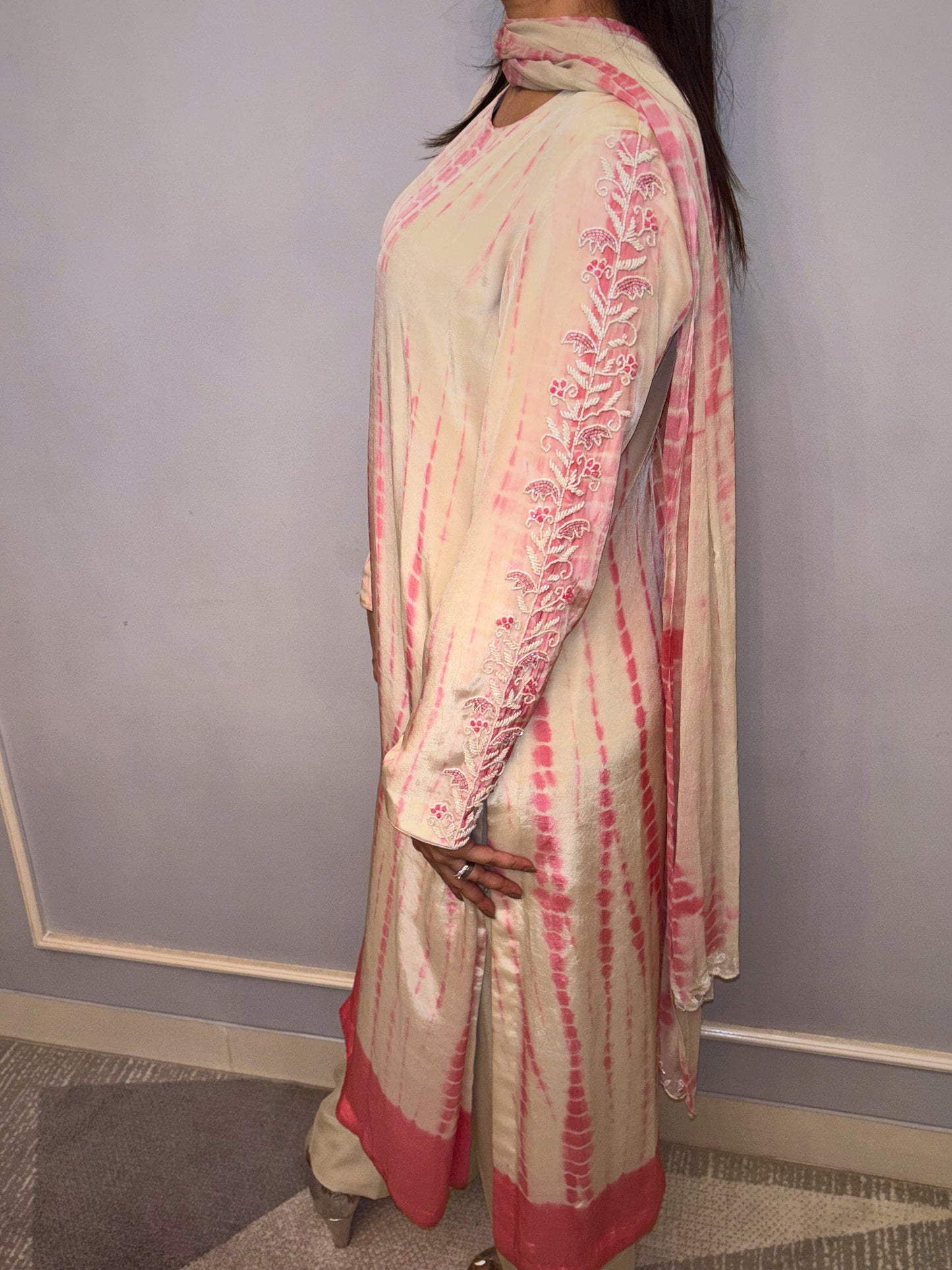 This elegant three-piece ensemble showcases a unique tie-dye pattern in soft cream and delicate rose hues with hand &amp; neck handwork (zardousi work), creating a graceful and contemporary look. Intricate floral embroidery adorns the sleeves and extends to the back of the kurta, adding a touch of traditional artistry and refined detail. Delicate button accents further enhance its sophisticated charm.

Paired with comfortable bottoms and a matching dupatta, this set is perfect for celebrating special times