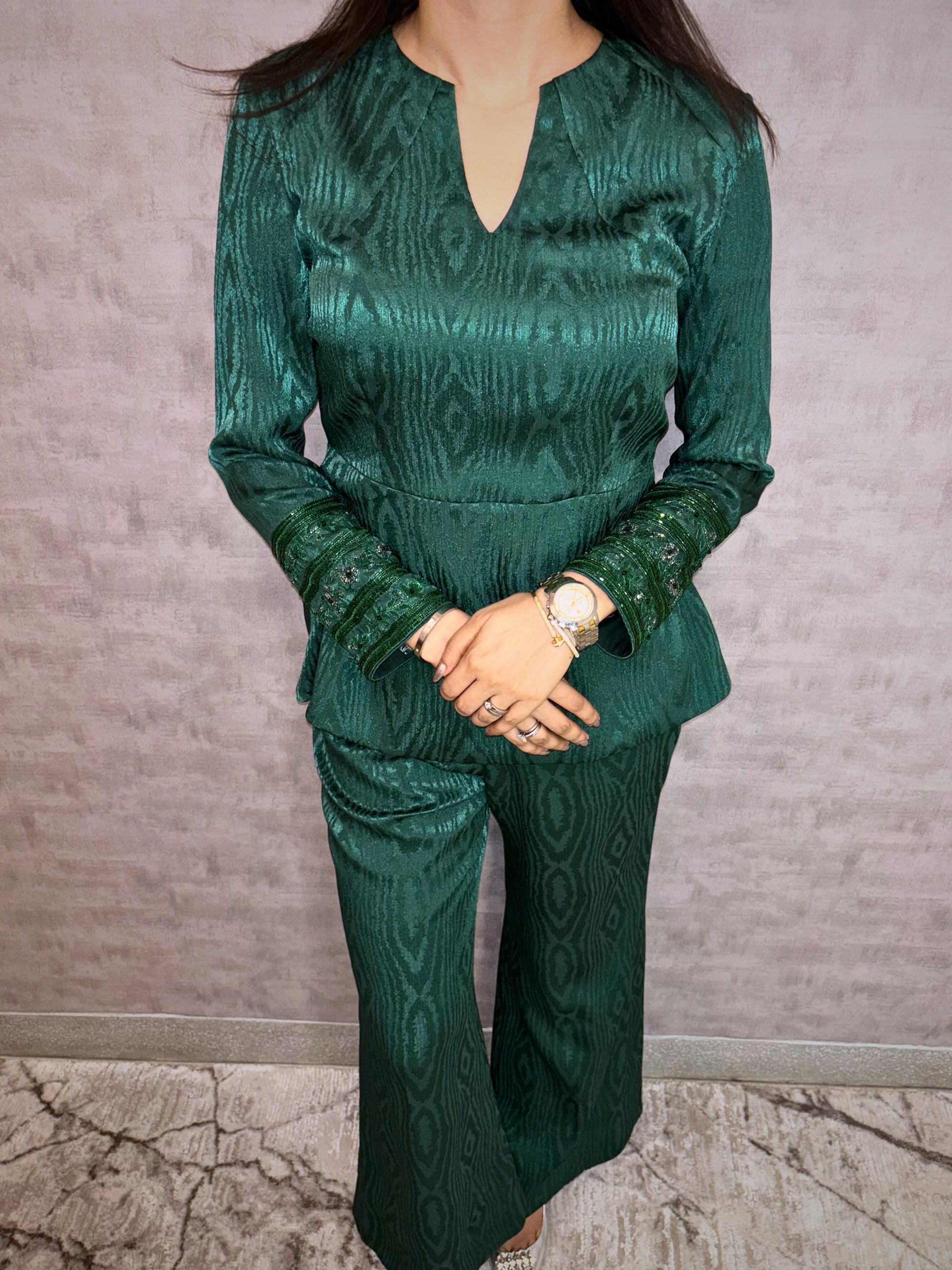 Presenting the Emerald Jewel Co-ord Set, a luxurious highlight from Taraashi's Platinum Collection. This stunning set features a rich, textured fabric in deep emerald green that glows with subtle sheen. The elegantly structured top pairs with flowing trousers, while intricately embellished cuffs add a captivating sparkle. Embrace sophisticated glamour and the premium artistry unique to Taraashi Platinum.