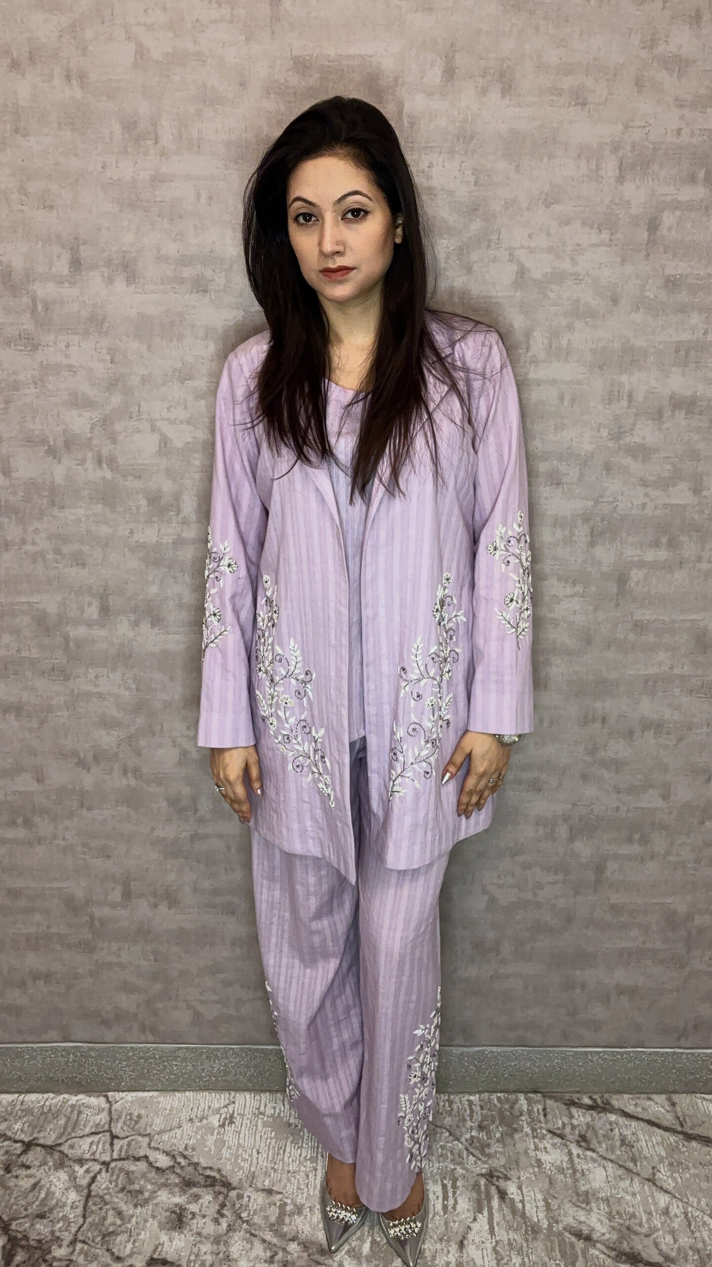 From Taraashi's exclusive Platinum Collection, this charming lilac ensemble offers sophisticated ease. Subtle stripes meet delicate silver or white embroidery gracing the flowing jacket and trousers. The three-piece set blends soft texture with intricate artistry for a light, airy feel. Experience effortless elegance and the refined quality unique to our Platinum pieces.