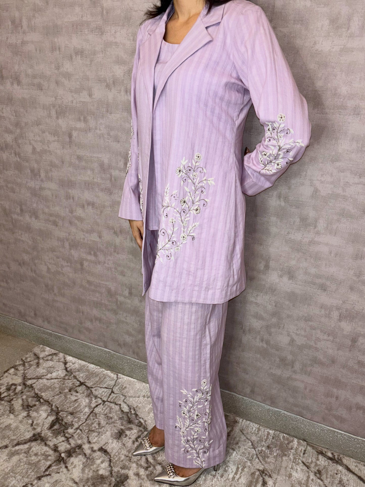From Taraashi's exclusive Platinum Collection, this charming lilac ensemble offers sophisticated ease. Subtle stripes meet delicate silver or white embroidery gracing the flowing jacket and trousers. The three-piece set blends soft texture with intricate artistry for a light, airy feel. Experience effortless elegance and the refined quality unique to our Platinum pieces.