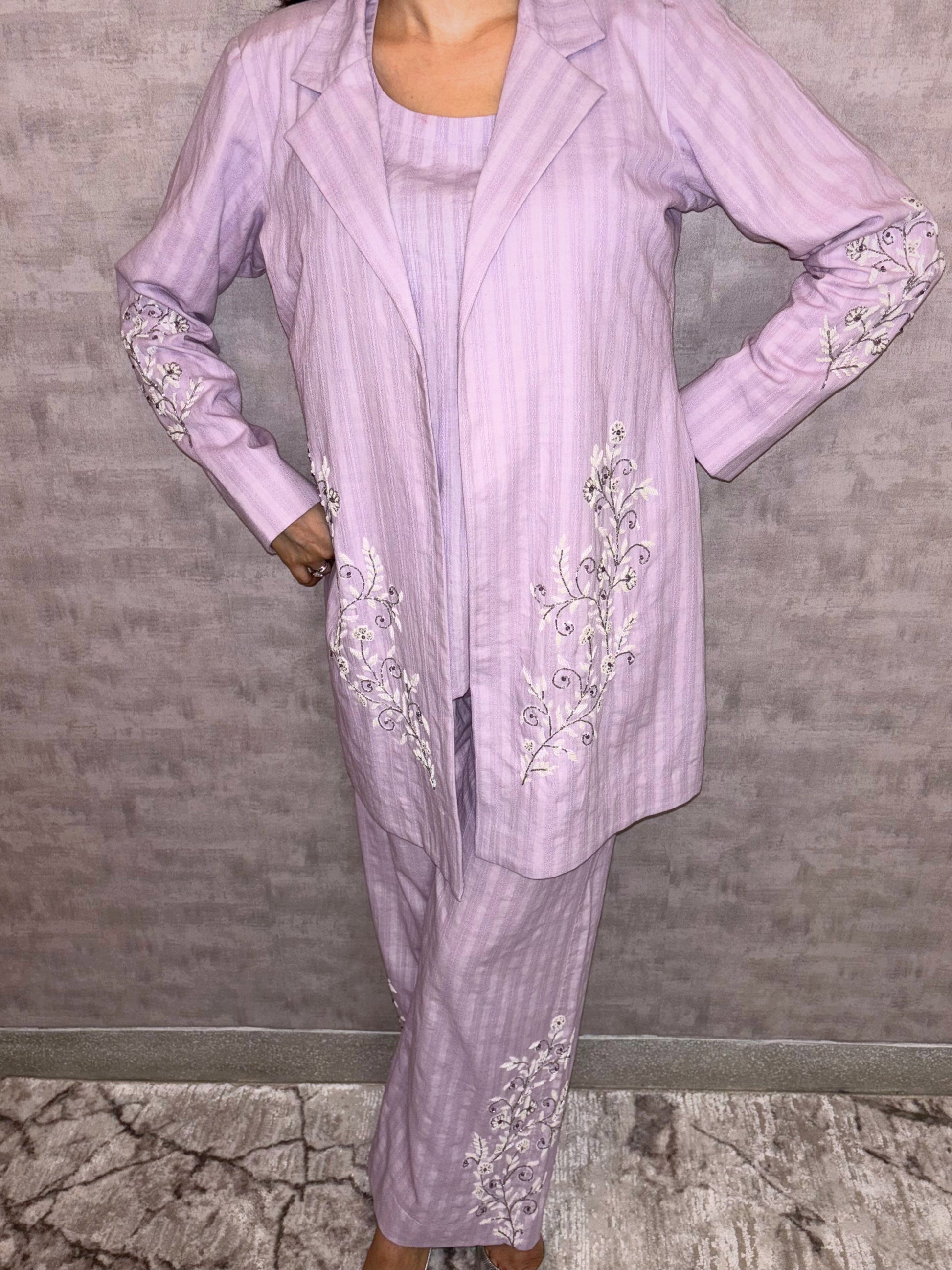 From Taraashi's exclusive Platinum Collection, this charming lilac ensemble offers sophisticated ease. Subtle stripes meet delicate silver or white embroidery gracing the flowing jacket and trousers. The three-piece set blends soft texture with intricate artistry for a light, airy feel. Experience effortless elegance and the refined quality unique to our Platinum pieces.