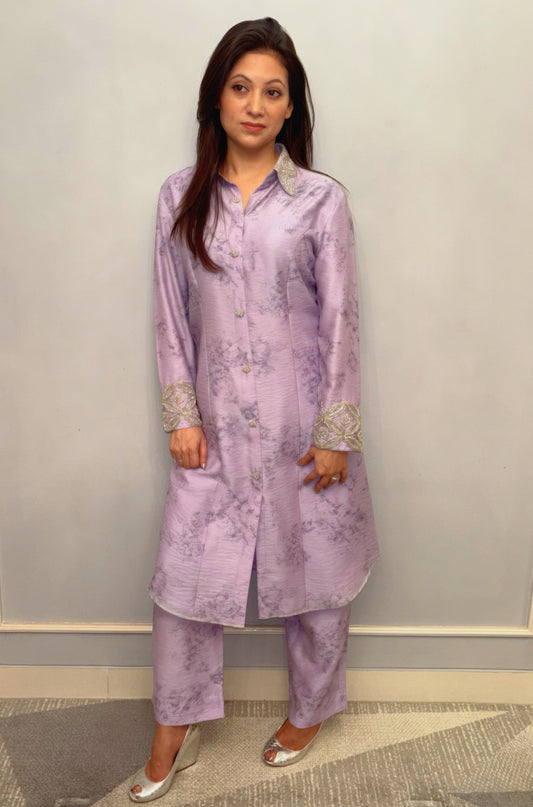 Bathed in the soft luminescence of a lilac dawn, this Taraashi Kurti Set exudes a quiet yet captivating sophistication. The flowing silhouette, adorned with delicate silver handwork (zardousi work) at the collar and cuffs, speaks of refined artistry.

The subtle texture of the fabric adds depth to the serene hue, creating an ensemble that is both graceful and contemporary. It's an expression of understated luxury, perfect for moments where poise and elegance take center stage.
