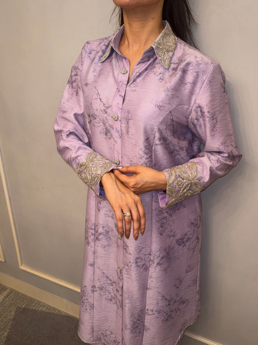 Bathed in the soft luminescence of a lilac dawn, this Taraashi Kurti Set exudes a quiet yet captivating sophistication. The flowing silhouette, adorned with delicate silver handwork (zardousi work) at the collar and cuffs, speaks of refined artistry.

The subtle texture of the fabric adds depth to the serene hue, creating an ensemble that is both graceful and contemporary. It's an expression of understated luxury, perfect for moments where poise and elegance take center stage.