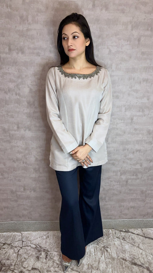 From Taraashi's exclusive Platinum Collection, introducing the Platinum Sheen Set. This elegant ensemble glows with a soft, metallic luster in a sophisticated neutral hue. The smooth fabric drapes beautifully in a chic tunic and matching trouser silhouette. Intricate dark embroidery adorns the graceful neckline, adding a touch of captivating contrast. Experience refined luxury and effortless poise unique to our Platinum designs.